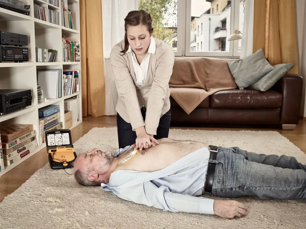 Wiederbelebung mit Defibrillator (AED): Eine Ersthelferin führt eine Herzdruckmassage durch.