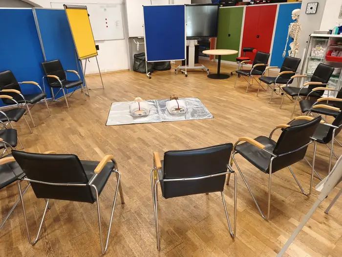 Schulungsraum der ASB Erste-Hilfe-Kurse in Bad Kreuznach mit Stuhlkreis, Übungspuppen und anatomischem Modell.